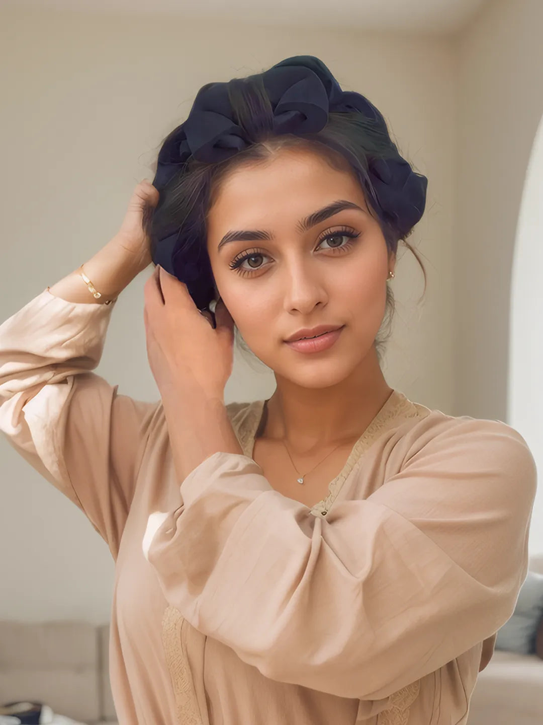 Woman wearing a black headscarf and beige blouse indoors
